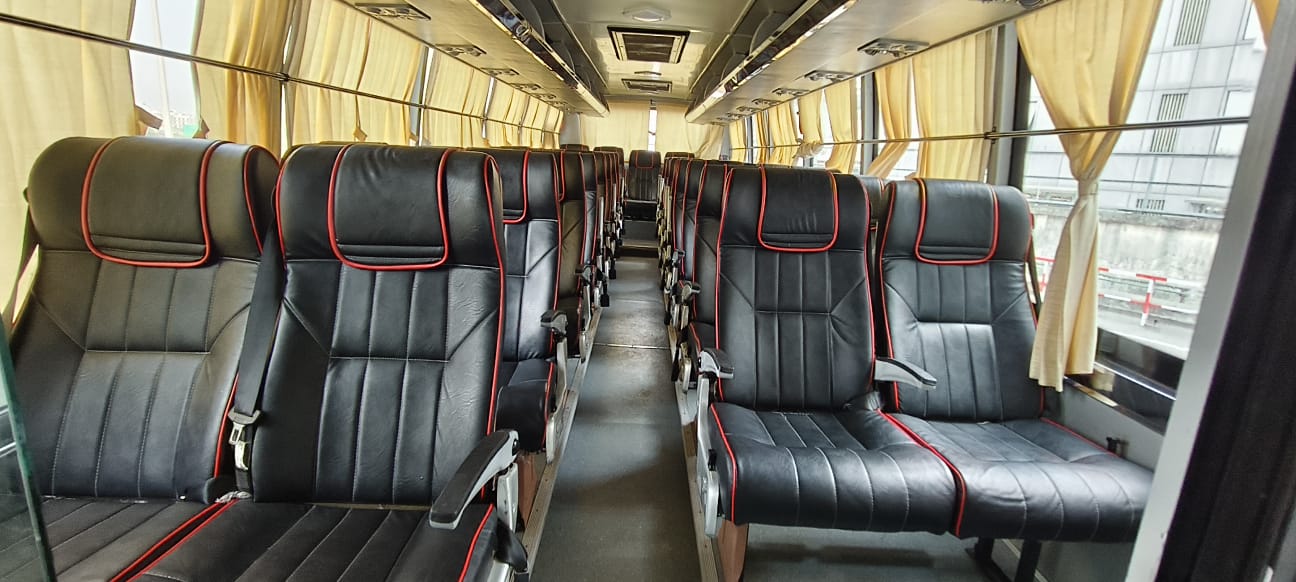 Luxury coach bus interior with black reclining seats for large group travel
